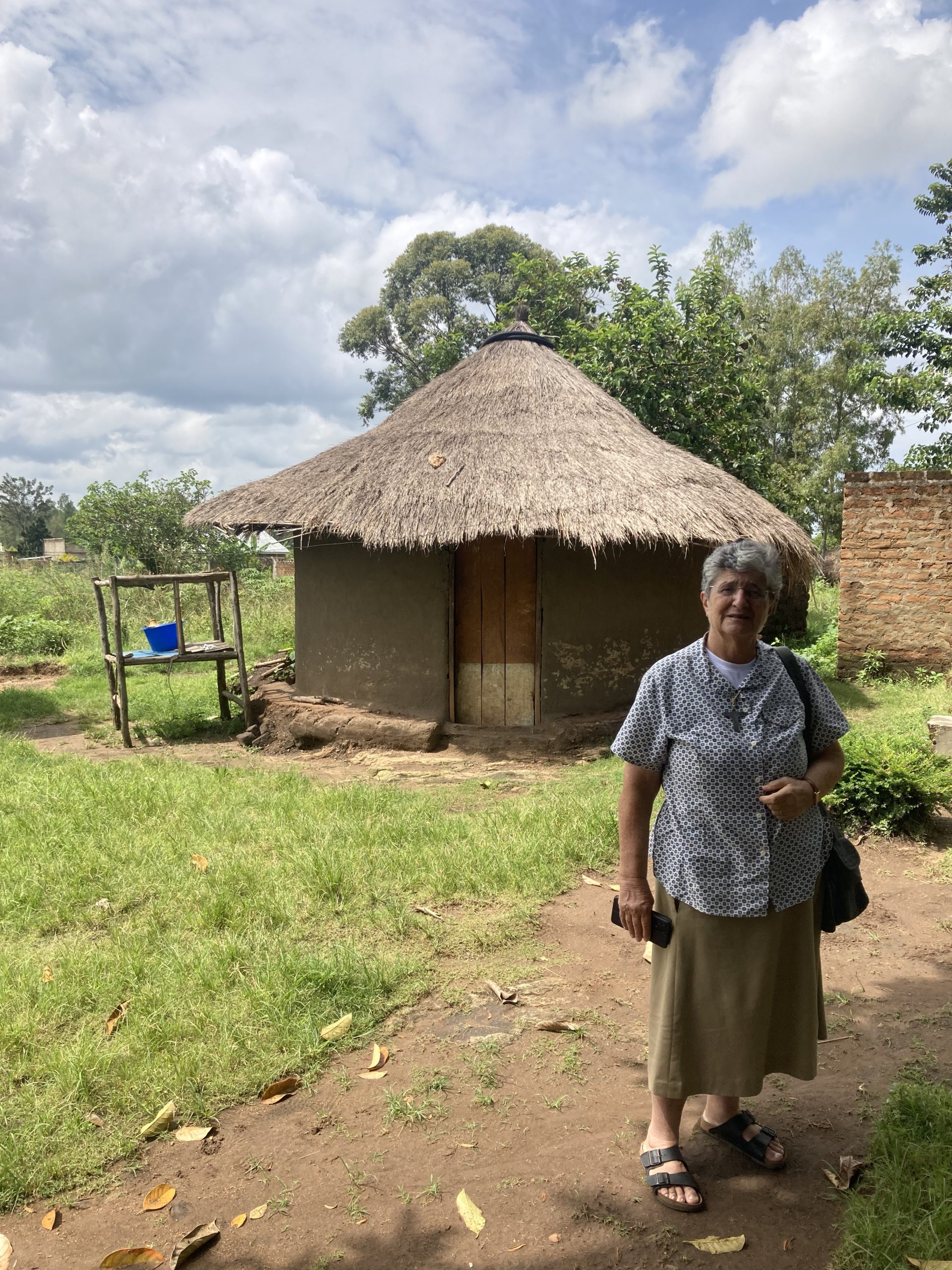 Sr Laura accanto a una abitazione tipica delle zone rurali ugandesi.
